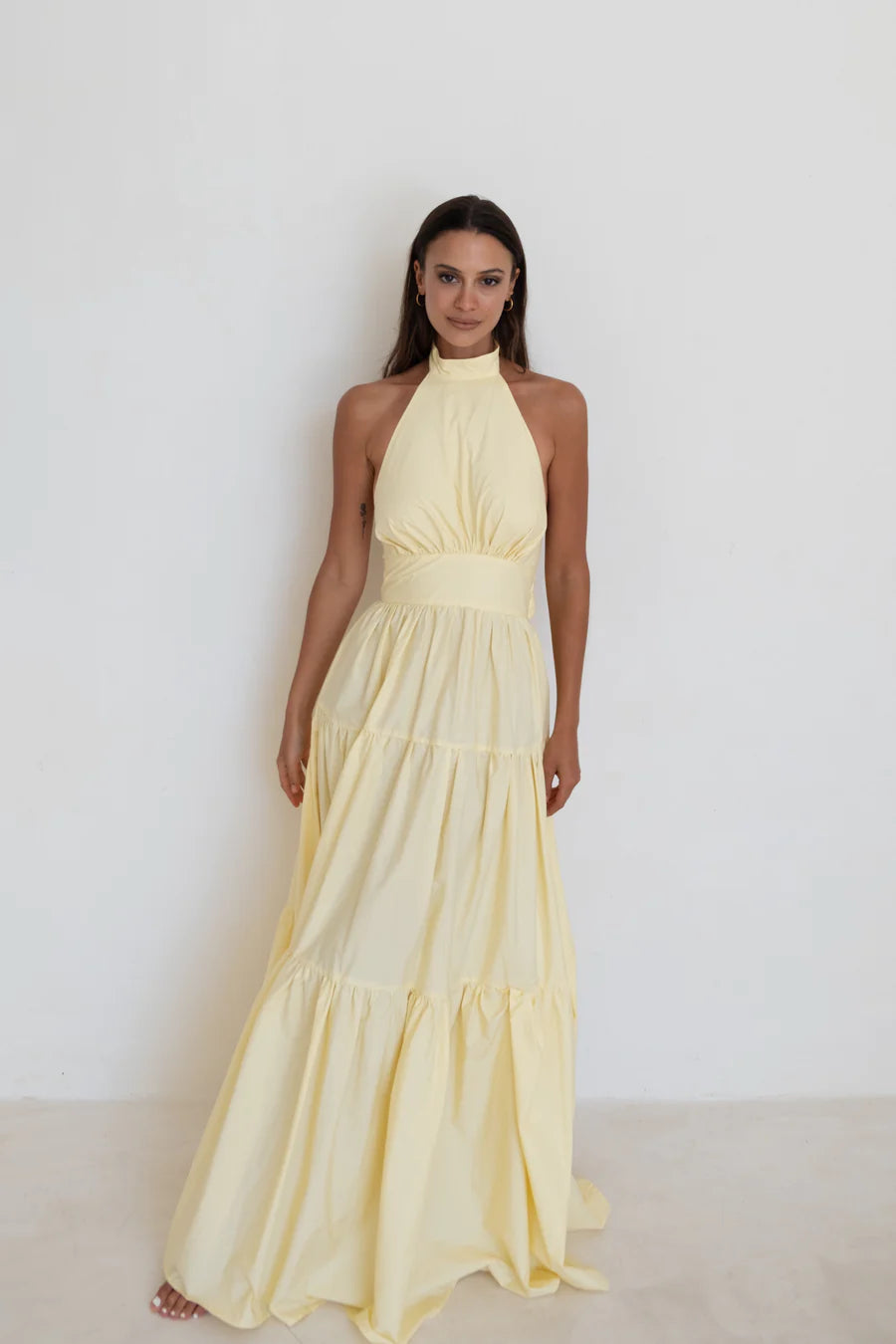 Model showcasing tiered skirt and halter neck Audrey Dress in Butter Yellow with halter neck - designer dress rental from Lend the Label