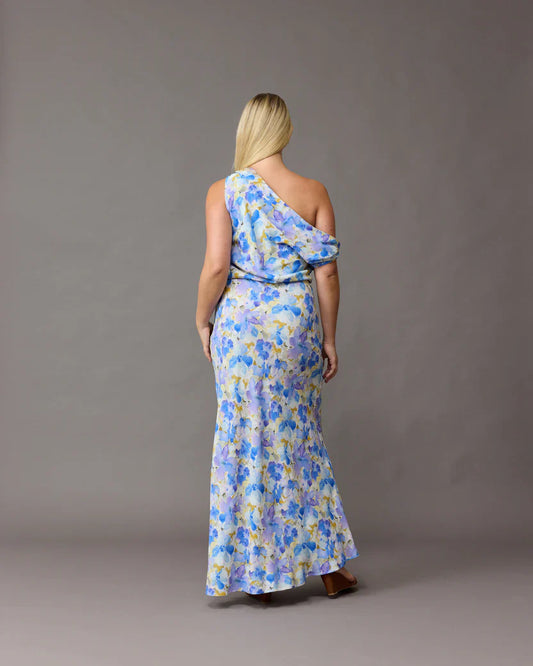 Back view of a woman wearing a one-shoulder Melon Maxi Dress in blueberry floral crepe, size 14.