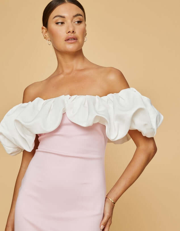 Cotton-rich fabric with a touch of nylon. Pink slim fit of dress with white off the shoulder ruffled details. Model showing front.