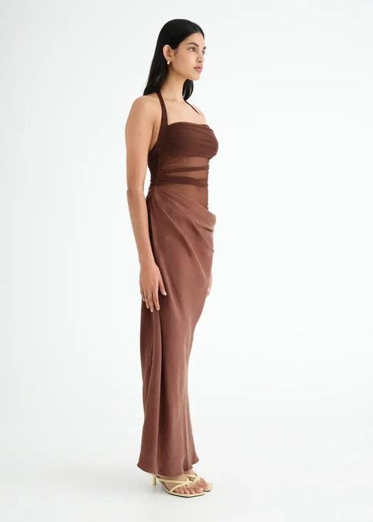 Side view of a woman in a brown Gina Maxi Dress featuring a halter mesh top and cowl detail on the skirt.