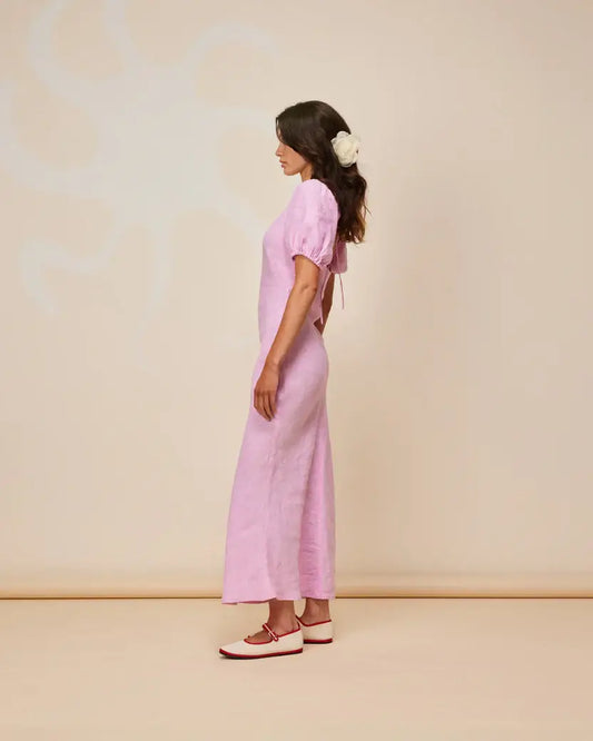 Model showcasing the KOS Linen Maxi Dress in soft pink, featuring puff sleeves and a cut-out back.