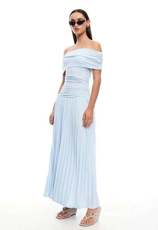 Model wearing Lioness Maxi dress in light blue, showcasing off-the-shoulder design and pleated skirt for effortless glamour.