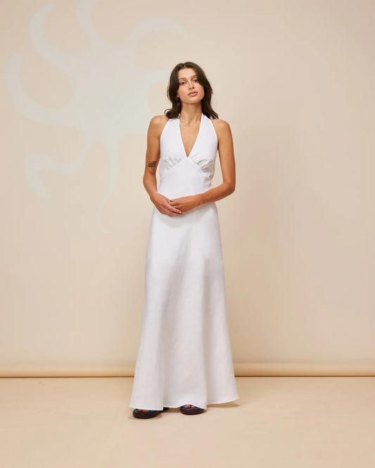 Ava Linen Halter Maxi Dress modeled by a woman in a crisp white linen fabric with a halter neckline and long silhouette.