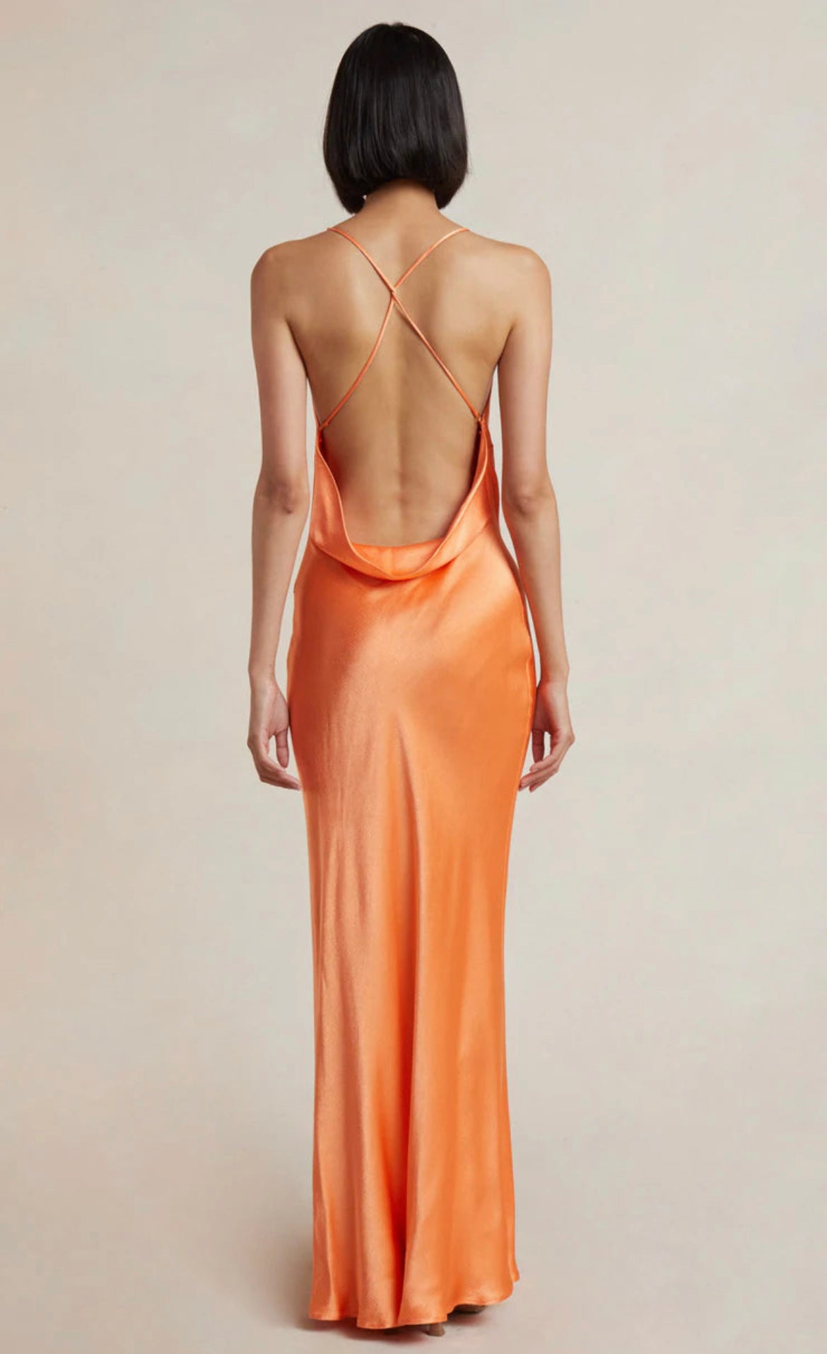 Model wearing the Annika Cowl Maxi Dress in Sorbet by Bec and Bridge. Showcasing back of dress with halter neck and rouleau straps