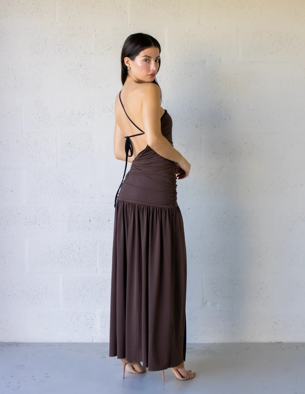 Lena Maxi Dress with asymmetrical style, gathered bodice, side cut-outs, and flowy skirt in brown color.