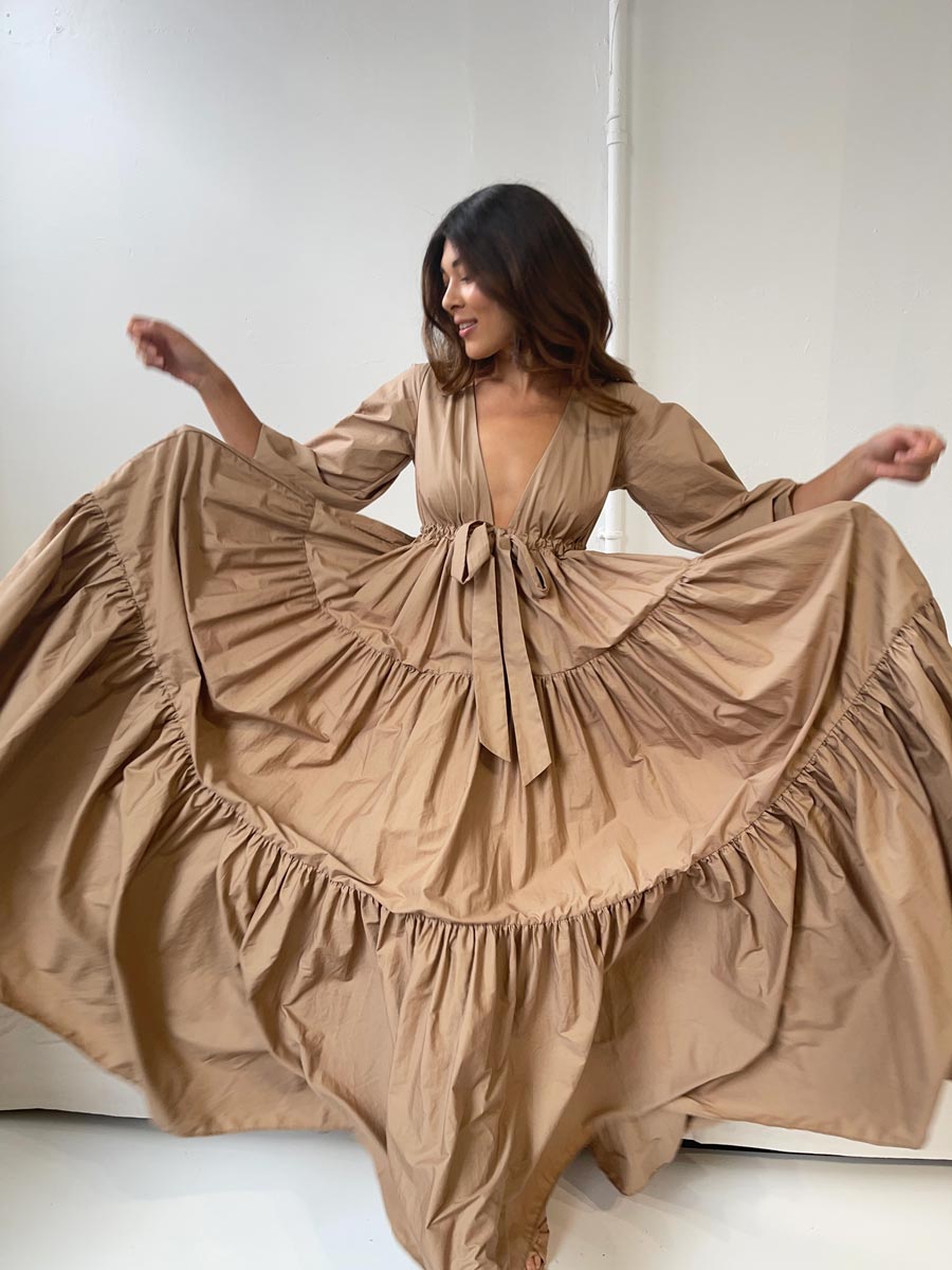 Model wearing A Winters Tale Dress in Tan, featuring a bow-tie and ruffled skirt, perfect for special occasions.