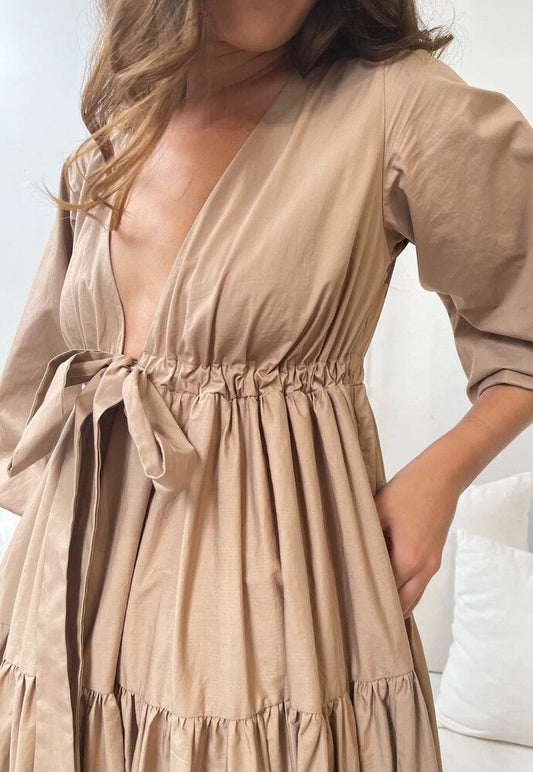 A Winters Tale Dress in Tan featuring a deep V-neck and adjustable bow-tie, perfect for special occasions.